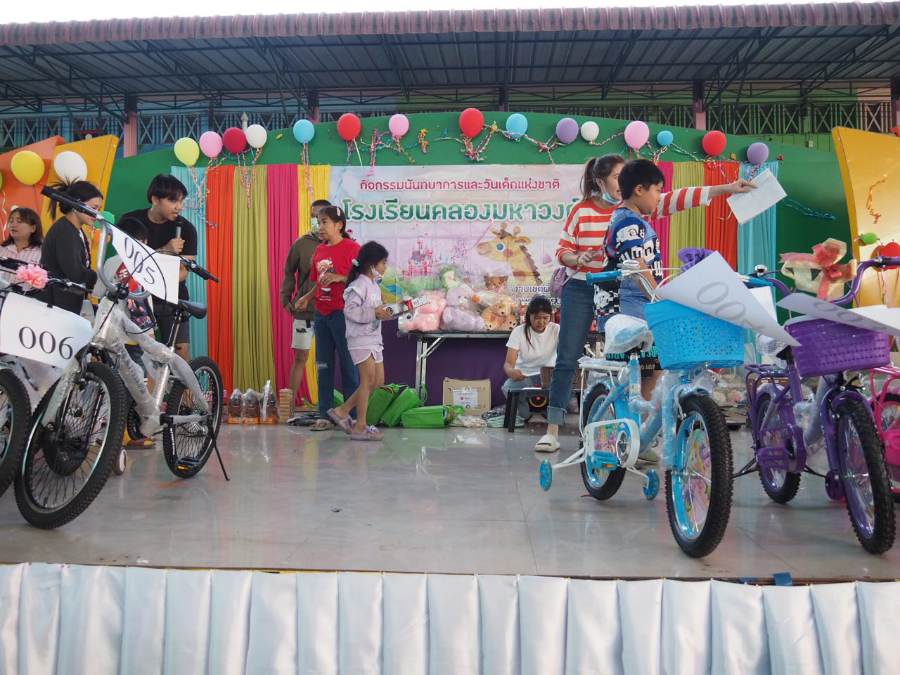 โรงเรียนคลองมหาวงก์จัดงานวันเด็กคึกคัก เมื่อเวลา 13.00น.วันที่ 10 มกราคม พ.ศ.2568 ที่โรงเรียนคลองมหาวงก์ เลขที่ 239 ม.2 ต.บางเมือง อ.เมืองสมุทรปราการ จ.สมุทรปราการได้จัดกิจกรรมวันเด็กแห่งชาติ โดยมีผู้ใหญ่ใจดี ร่วมสนับสนุนของขวัญ ขนมและทุนการศึกษาจำนวนมากในการกิจกรรมวันเด็กแห่งชาติในครั้งนี้ โดยมีคณะครูอาจารย์โรงเรียนคลองมหาวงก์รวมทั้งน.ส.ขวัญเรือน นาคทิม กำนันตำบลบางเมือง พร้อมเจ้าหน้าที่ฝ่ายปกครองรวมทั้งผู้ใหญ่ใจดีร่วมกันจัดกิจกรรม และได้รับเกียรติจากนาวาเอก อนุศักดิ์ นาคทิม นายกเทศมนตรีตำบลบางเมือง เข้าร่วมกิจกรรมดังกล่าวด้วย โดยมีเด็กนักเรียนจำนวนมากเข้าร่วมกิจกรรมและรับของแจกที่ผู้ใหญ่ใจดีนำมามอบให้ ขณะที่โดยรอบโรงเรียนได้มีอาหาร น้ำดื่ม ขนม มาแจกเด็กๆทุกคนที่เข้ามาร่วมงาน ภายในงานได้มีของรางวัลวางเรียงรายบนเวทีจำนวนมาก อาทิ รถจักรยาน พัดลม ตุ๊กตา เงินสด และของรางวัลอื่นๆจำนวนมาก โดยมีกิจกรรมต่างๆ อาทิ การแสดงของครูอาจารย์ ที่แต่งตัวเป็นเด็กนักเรียนออกมาแสดงโชว์ สร้างสีสันภายในงานได้เป็นอย่างดี ขณะที่คณะครูอาจารย์ อยากให้เด็กนักเรียนทุกคนได้รางวัล ไม่อยากให้กลับบ้านมือเปล่า จึงได้จับเบอร์ เพื่อให้นักเรียนได้ลุ้นรางวัลกันทุกคนและเดินเข้าแถวรับรางวัลอย่างเป็นระเบียบ สร้างรอยยิ้มให้กับเด็กๆทุกคนที่มาร่วมงานเป็นอย่างมาก